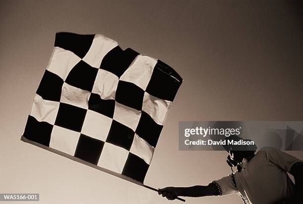 man holding checkered flag (toned b&w) - checkered flag stock-fotos und bilder