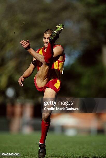 australia rules football player kicking ball - australian rules football ball stock pictures, royalty-free photos & images