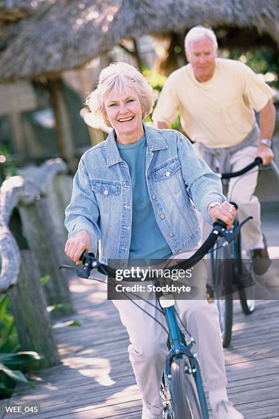 woman and man riding bicycles along wooden sidewalk - human powered vehicle stock pictures, royalty-free photos & images