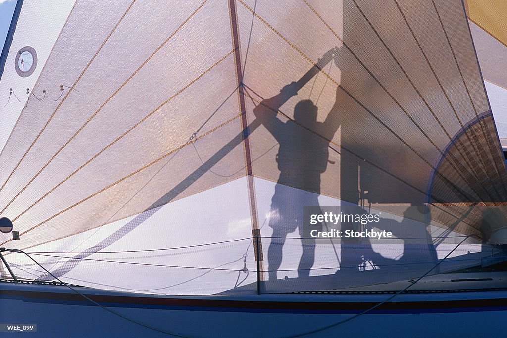 Silhouette of two men preparing sail on sailboat