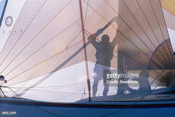 silhouette of two men preparing sail on sailboat - scheepsonderdeel stockfoto's en -beelden