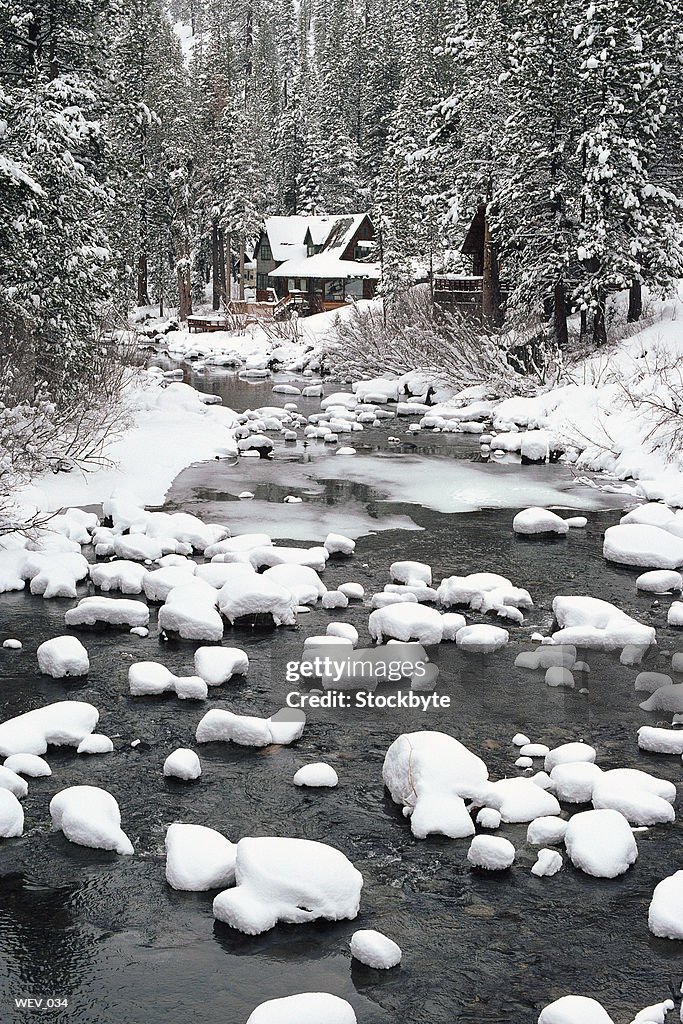 Winter view of mountain stream with cabin in distance