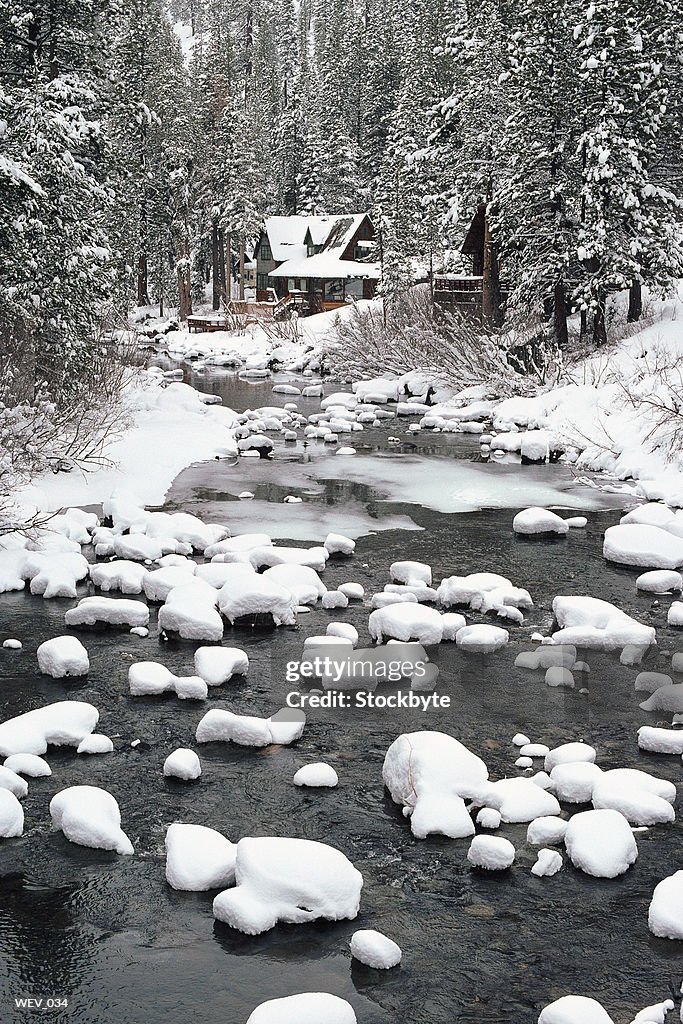 Winter view of mountain stream with cabin in distance