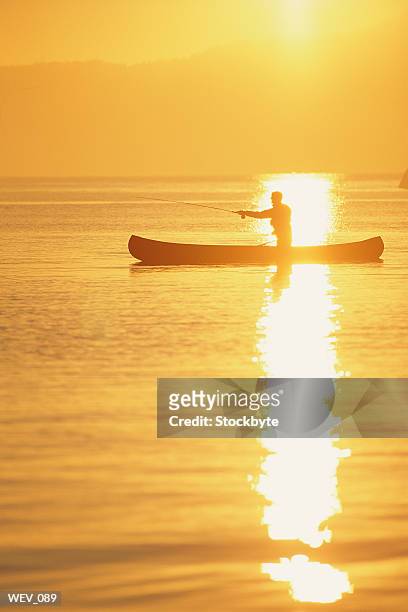 man fishing from canoe at sunset - from to stock pictures, royalty-free photos & images