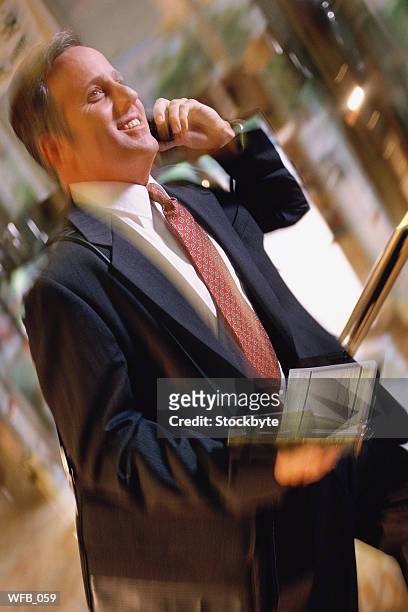 man using cellular phone, holding open date book in other hand - only mid adult men stock pictures, royalty-free photos & images
