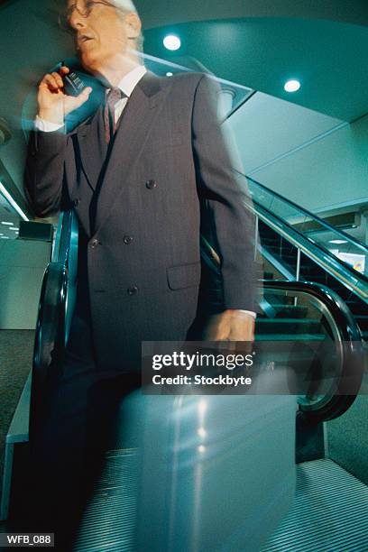 businessman walking away from escalator - from to foto e immagini stock