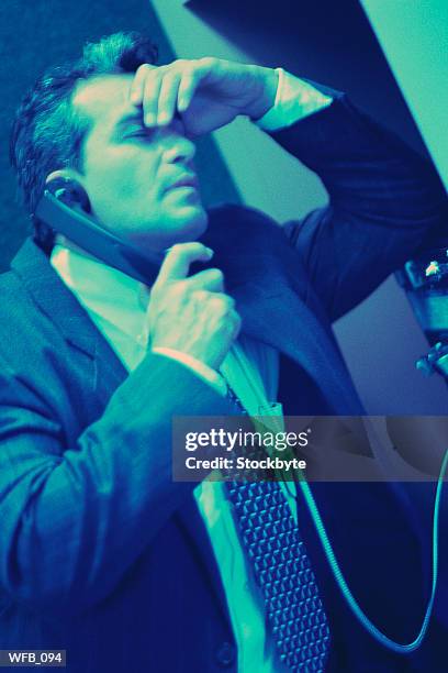 man rubbing forehead, using public telephone - only mature men imagens e fotografias de stock