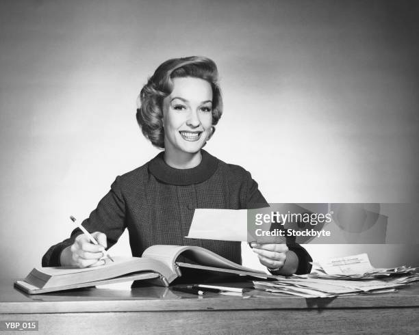 woman holding pencil and paper, open book in front of her - alleen mid volwassen vrouwen stockfoto's en -beelden