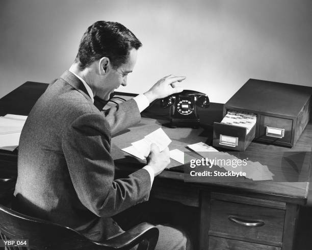 man reaching for phone while reading card - alleen oudere mannen stockfoto's en -beelden