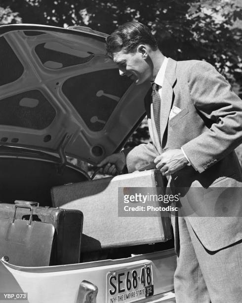 man loading trunk of car - of fotografías e imágenes de stock