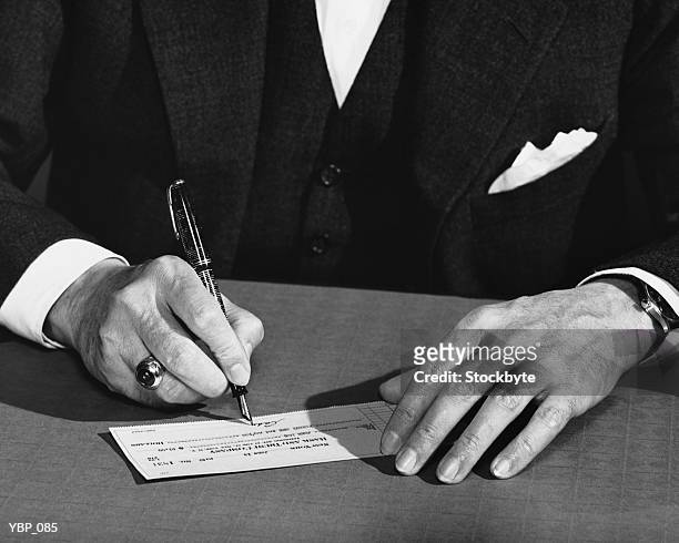hand shot of man signing check - writing instrument fotografías e imágenes de stock