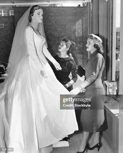 duas mulheres olhando no vestido de noiva manequim em - equipamento de varejo - fotografias e filmes do acervo