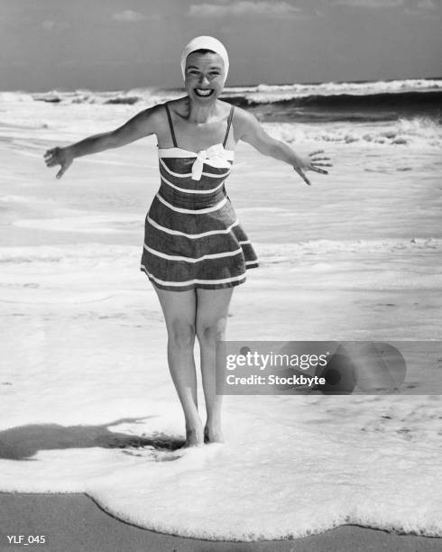 woman standing in shallow water at ocean - maillot vert stock pictures, royalty-free photos & images