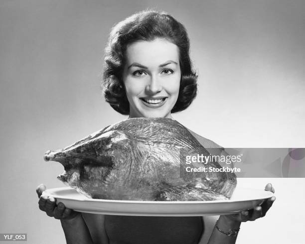 woman holding platter with roast turkey - alleen mid volwassen vrouwen stockfoto's en -beelden
