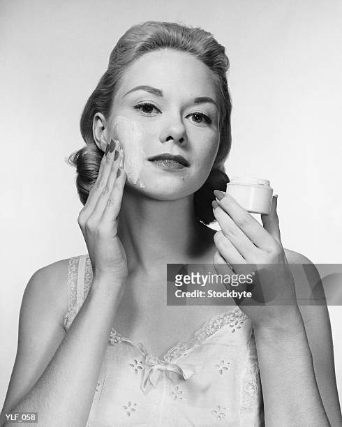 woman putting cream on face - alleen mid volwassen vrouwen stockfoto's en -beelden