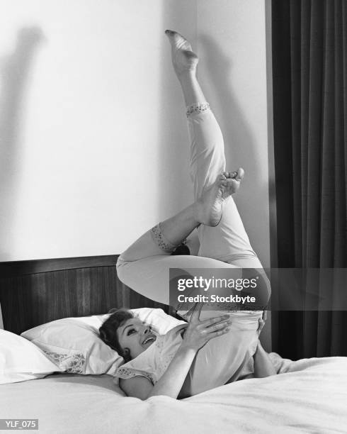 woman lying on bed, doing exercises - duing stock pictures, royalty-free photos & images