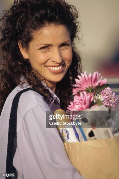 woman holding grocery bag with flowers - alleen mid volwassen vrouwen stockfoto's en -beelden