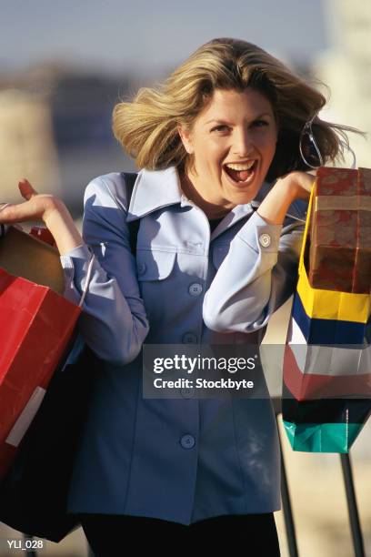woman holding up shopping bags, laughing - sólo mujeres de mediana edad fotografías e imágenes de stock