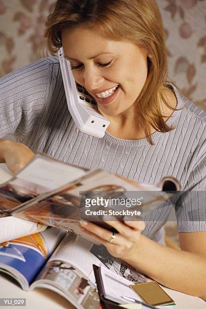 woman talking on cordless phone and looking at photographs - out and about stock-fotos und bilder
