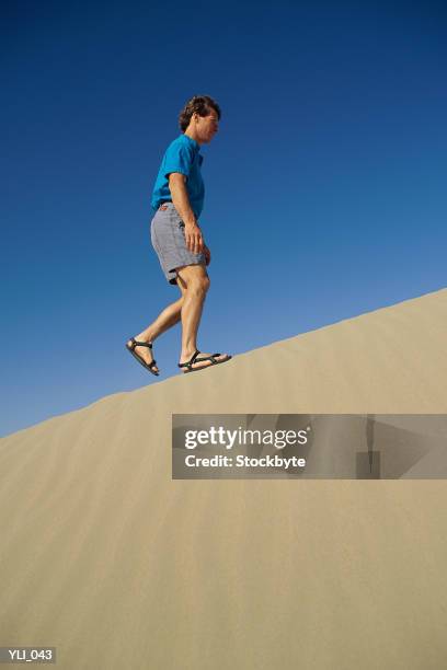 man walking up sand dune - only mid adult men stock-fotos und bilder