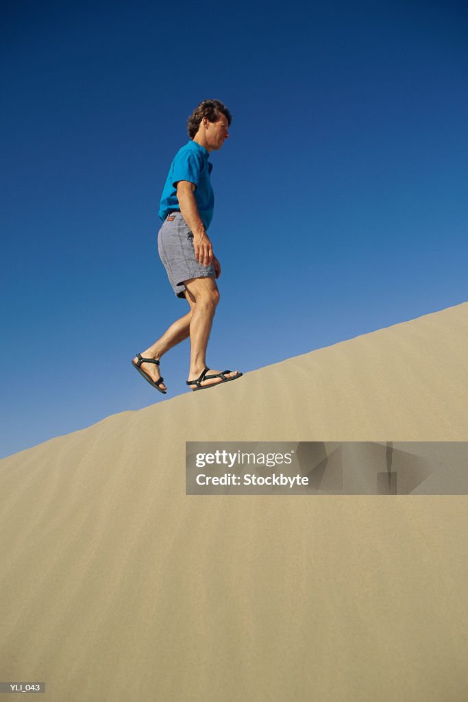 Man walking up sand dune