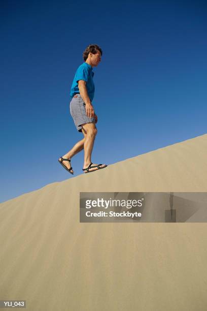 man walking up sand dune - only mid adult men stock pictures, royalty-free photos & images