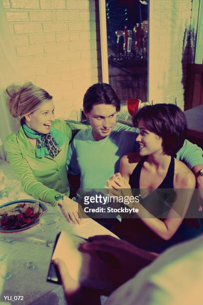 man and two women in restaurant book - in between stock-fotos und bilder