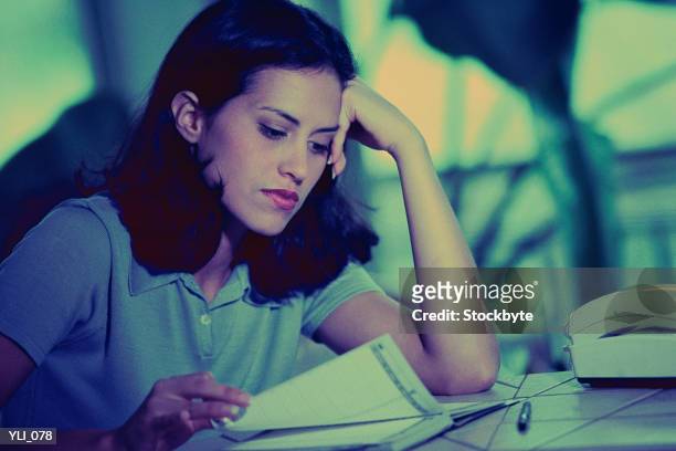 woman sitting in front of telephone, looking through appointment book - alles in einem stock-fotos und bilder