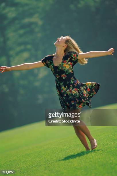 woman twirling in field, arms raised level with shoulders - menselijke ledematen stockfoto's en -beelden
