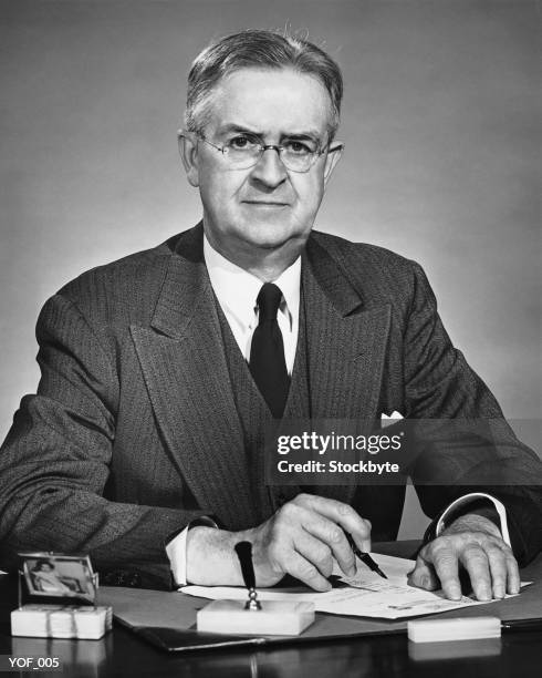 man sitting at desk, holding pen - only mature men stock pictures, royalty-free photos & images