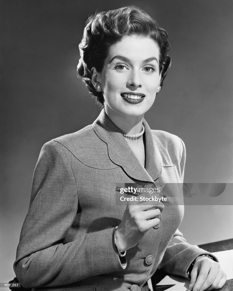 Femme souriante, tenant un stylo