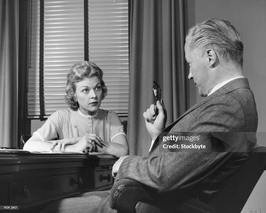 Man talking to woman who is taking notes