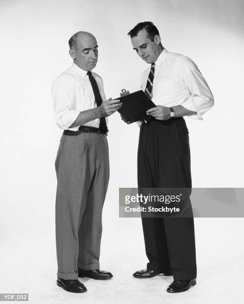 two men standing, looking at clipboard - alleen oudere mannen stockfoto's en -beelden