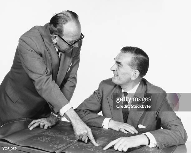 two men, one pointing to blueprint - alleen oudere mannen stockfoto's en -beelden