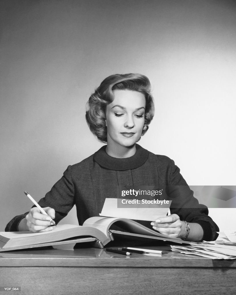 Woman looking at paper, holding pencil