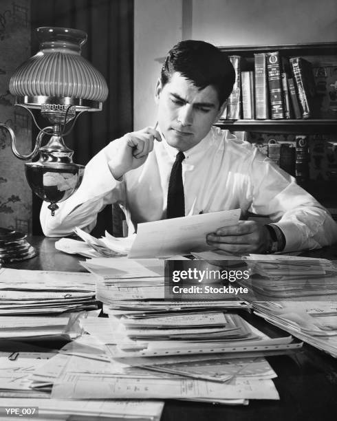 hombre trabajando en el escritorio cubierto con archivos - at fotografías e imágenes de stock