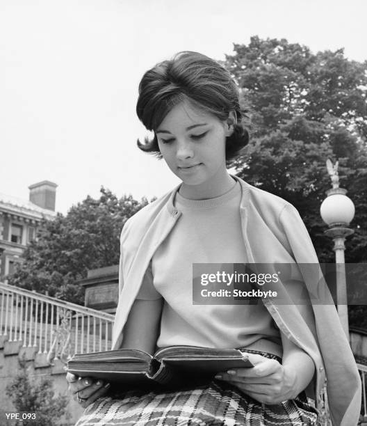 female student sitting outdoors, reading book - hundreds of super hero fans line up early as dc entertainment launches new era of comic books stockfoto's en -beelden