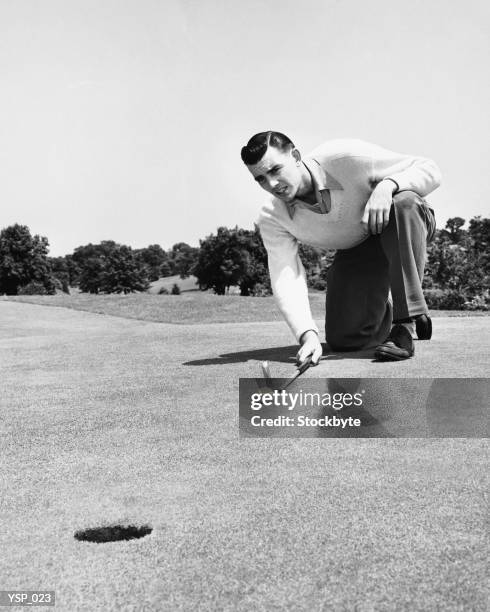 man lining up golf shot on putting green - endast medelålders män bildbanksfoton och bilder