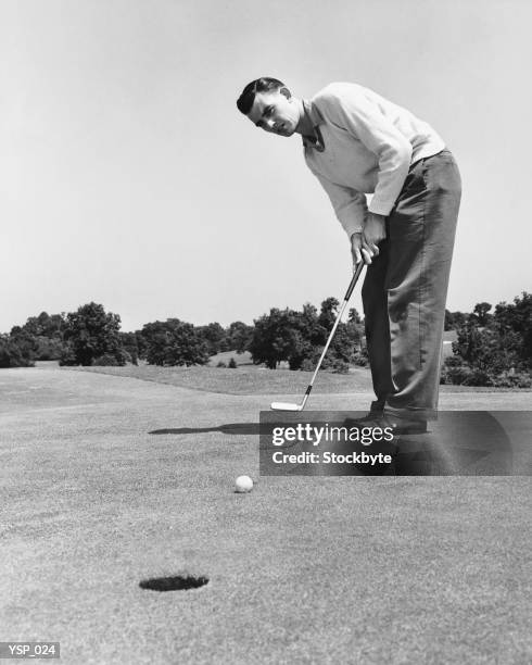 man watching golf ball after hitting it with putter - alleen oudere mannen stockfoto's en -beelden