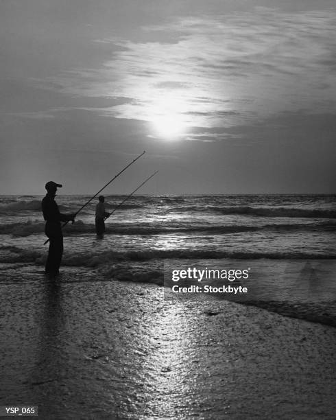 due uomo pesca dalla spiaggia al tramonto - non moving activity foto e immagini stock