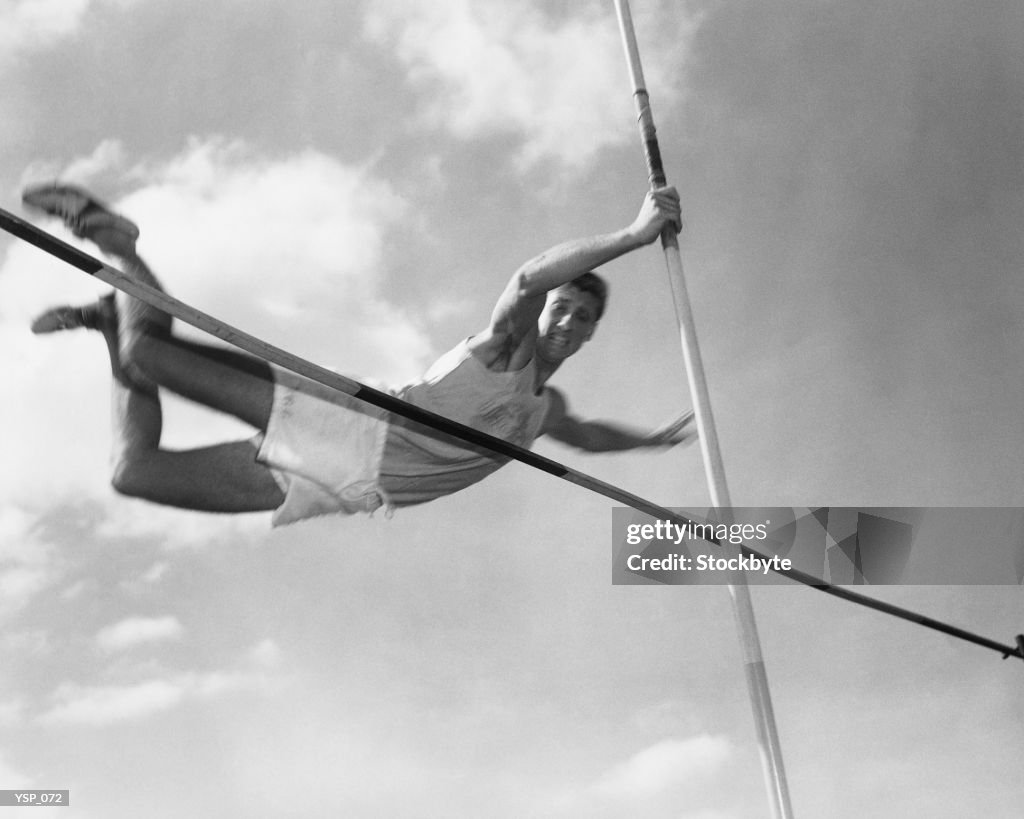 Male pole-vaulter clearing bar