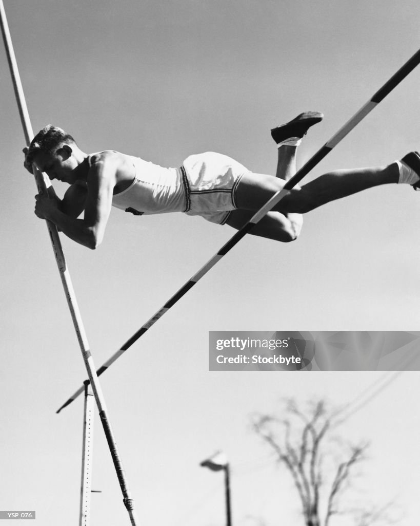 Male pole-vaulter clearing bar