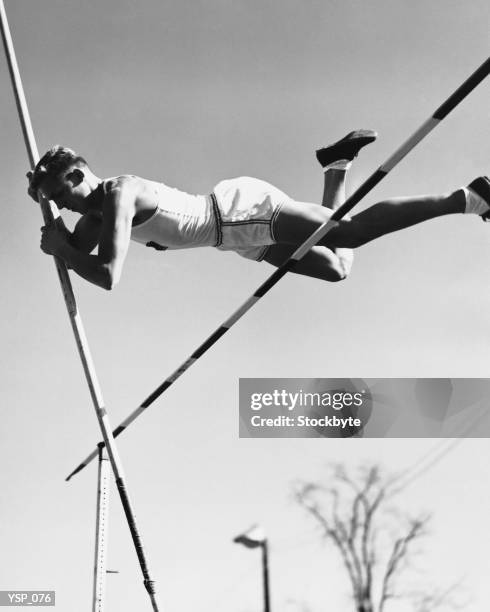 male pole-vaulter clearing bar - pole vault stock pictures, royalty-free photos & images