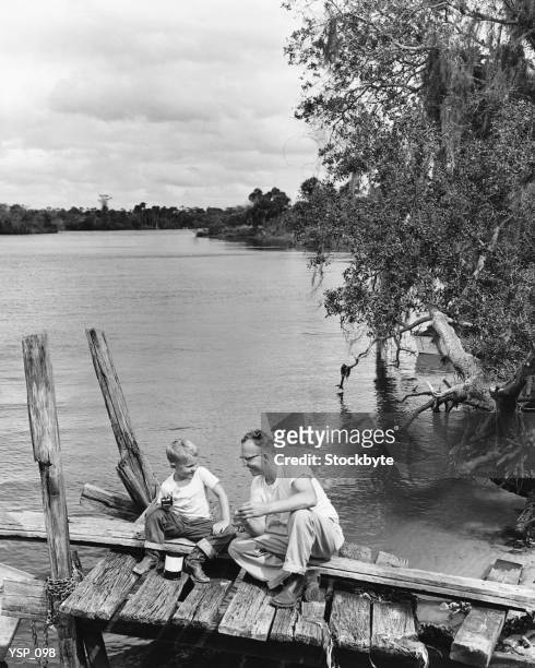 father and son sitting on dock getting ready to fish - years since the birth of benazir bhutto the 1st female leader of a muslim country stockfoto's en -beelden