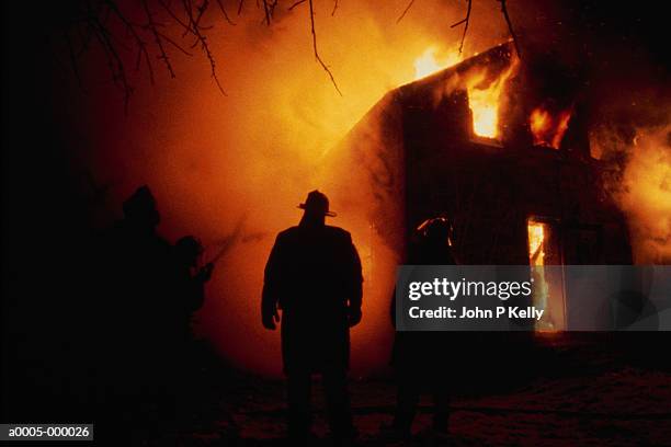 firefighter by flaming house - house fire stock-fotos und bilder