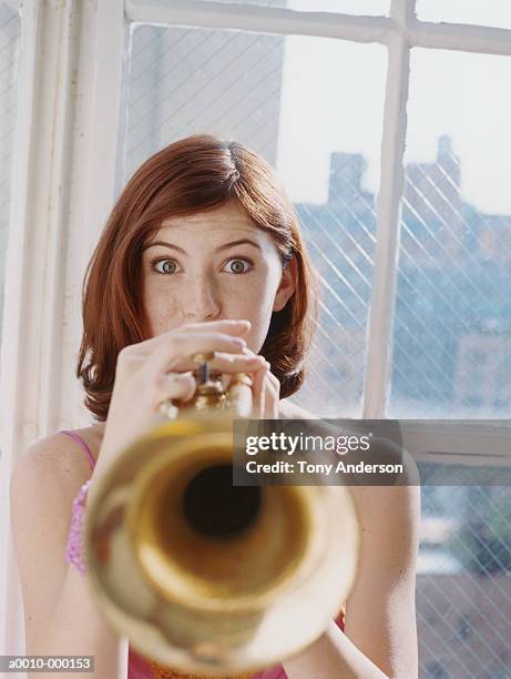 young woman playing trumpet - trumpet fotografías e imágenes de stock