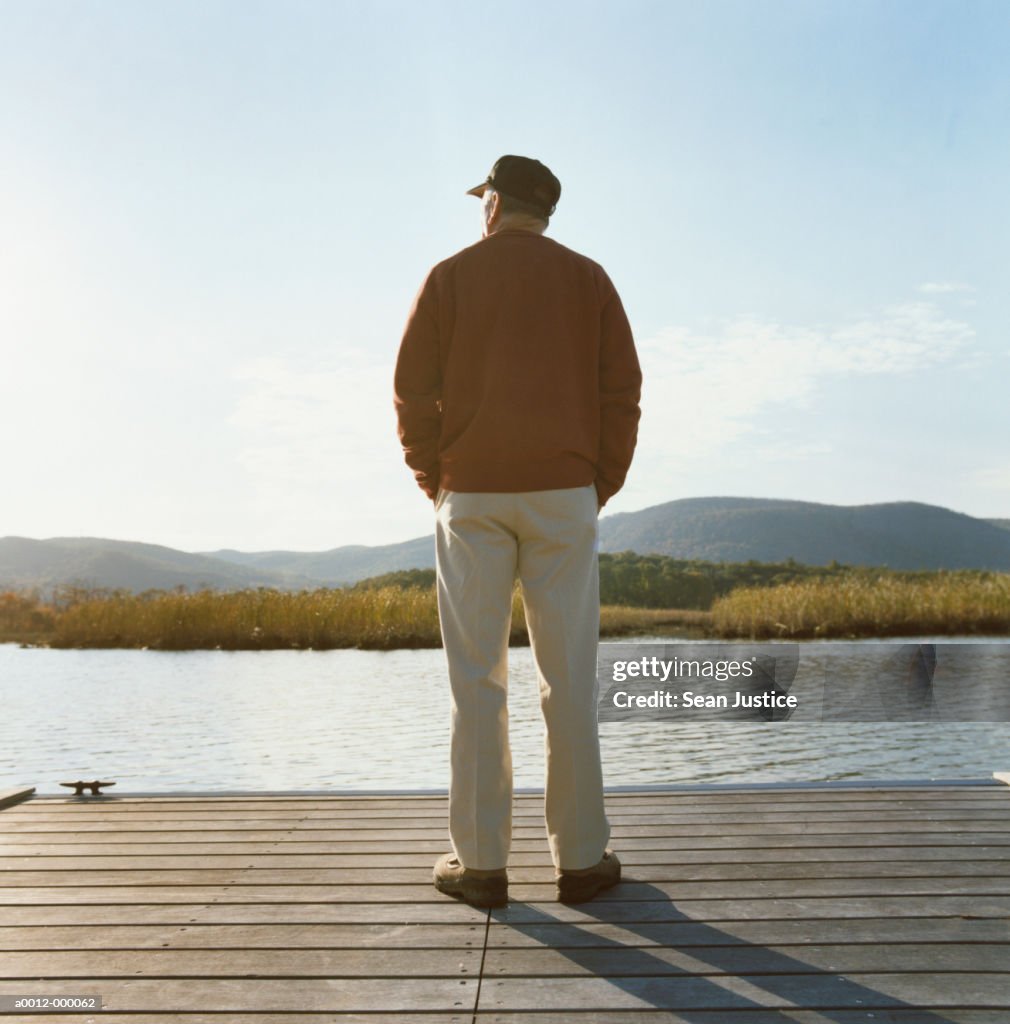 Man Standing on Pier near Lake