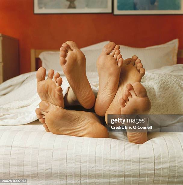 bare feet in bed - three people in bed stock pictures, royalty-free photos & images