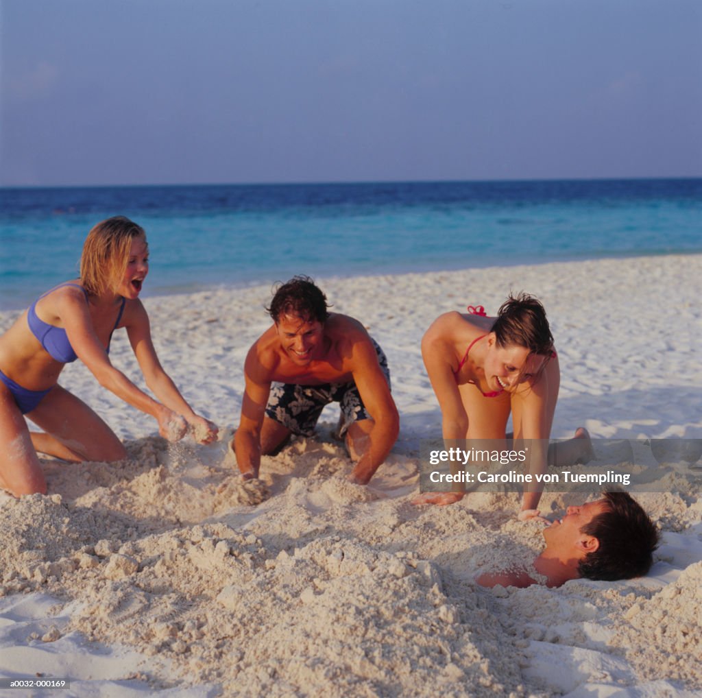 Group Burying Man in the Sand