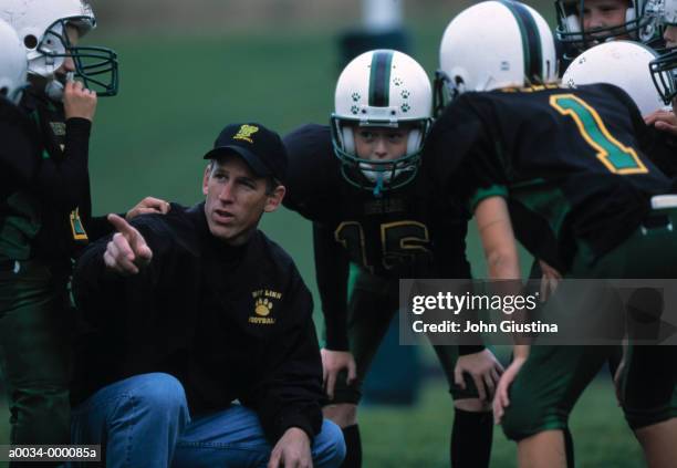 coach talks to football team - american football coach stock-fotos und bilder